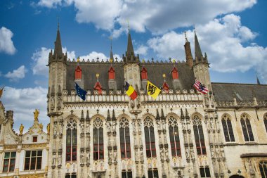 Tarihi şehir merkezinde ortaçağ mimarisi, kaldırım taşı sokakları, gotik kuleler ve canlı çiçek sergilerinin yer aldığı Bruges, Belçika 'nın resimli manzarası.