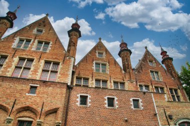 Tarihi şehir merkezinde ortaçağ mimarisi, kaldırım taşı sokakları, gotik kuleler ve canlı çiçek sergilerinin yer aldığı Bruges, Belçika 'nın resimli manzarası.