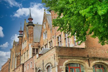 Tarihi şehir merkezinde ortaçağ mimarisi, kaldırım taşı sokakları, gotik kuleler ve canlı çiçek sergilerinin yer aldığı Bruges, Belçika 'nın resimli manzarası.