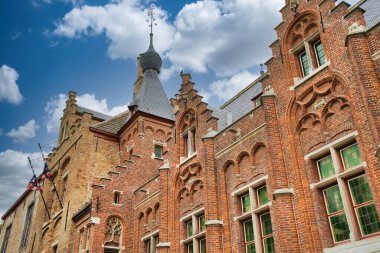 Tarihi şehir merkezinde ortaçağ mimarisi, kaldırım taşı sokakları, gotik kuleler ve canlı çiçek sergilerinin yer aldığı Bruges, Belçika 'nın resimli manzarası.