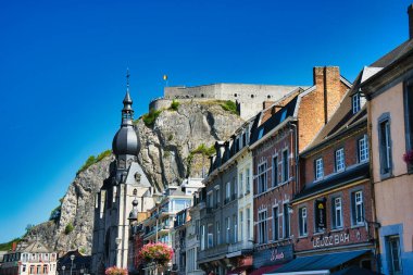 Dinant, Belçika 'nın manzarası. Tarihi Collegiate Kilisesi, uçurumdaki kale ve Meuse Nehri boyunca renkli binalar..