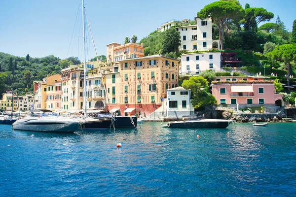 Harbor view of Portofino with sailing boats, yachts and the church of St. George on the hill in the background, Liguria, Italy.