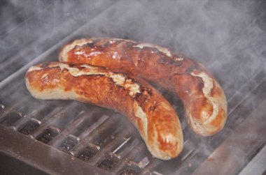 Zwei Bratwuerste auf dem Grill mit Dampf