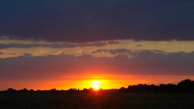 Langsam geht die Sonne Ta ki ben Horizont olana kadar Lila Wolken vor Silhuette von Wald und Feld
