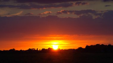 Langsam geht die Sonne Ta ki ben Horizont olana kadar Lila Wolken vor Silhuette von Wald und Feld