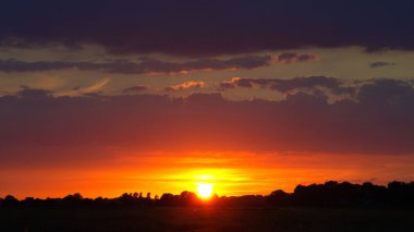 Langsam geht die Sonne Ta ki ben Horizont olana kadar Lila Wolken vor Silhuette von Wald und Feld