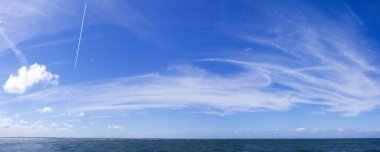 Dynamische Wolken auf blauem Himmel ueber Nordsee-Panorama
