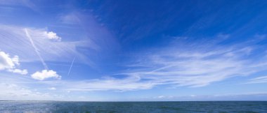 Dynamische Wolken auf blauem Himmel ueber Nordsee-Panorama