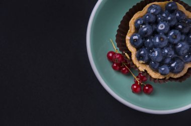 Koyu bir arka plan üzerinde yaban mersini ile tam tahıllı kum tartlet.