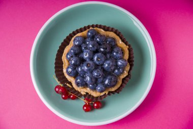 : Pembe bir arka plan üzerinde yaban mersini ile kepekli kum tartlet. Üstte görüntü