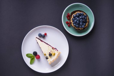 beze pasta ve yaban mersini ile tam tahıllı kum tartlet, siyah bir arka plan üzerinde. Üstte görüntü