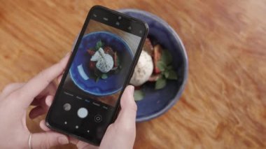 İtalyan burrata peyniri ile salata telefonda fotoğraf yapıyor Eller