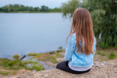 Nehrin kenarında tek başına oturan küçük kızın arka planı..