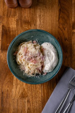 Pastırmalı makarna, pastırmalı fettucine ve ahşap arka planda peynir kreması. İtalyan yemeği konsepti. Sağlıklı, lezzetli yemekler. Diyet, tatiller, tarif konsepti. Seçici odak