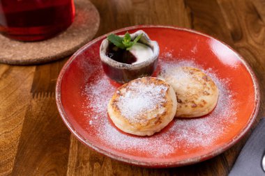 Meyve çaylı tatlı. Tahta masada kırmızı tabakta peynirli tatlı. Kafede nefis bir kahvaltı. Ev yapımı fırın. Yemek fotoğrafı..