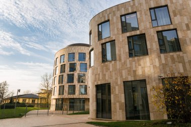 Çimleri ve ağaçları olan modern bir bina.