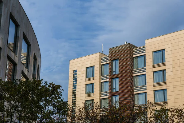 Modern building with lawn and trees around. A small business center or hotel in beige color