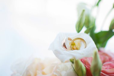 Gelin ve damadın alyansları bir buketin arka planında. Düğün konsepti