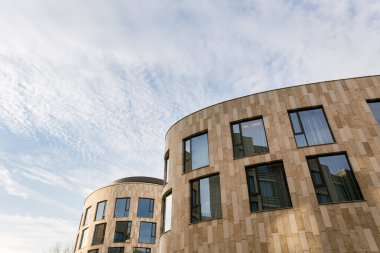 Çimleri ve ağaçları olan modern bir bina. Bej renkli küçük bir işletme merkezi ya da otel