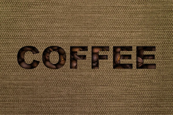 キャンバス地の袋を背景にコーヒー豆で作られたテキストコーヒー — ストック写真