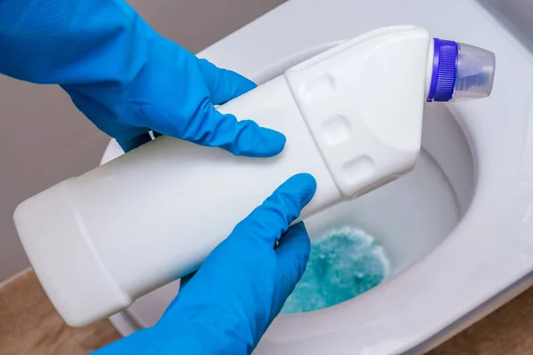 Clean toilet with cleaning agent bleaching gel and a gloved hand. The concept of the home cleaning, cleaning service