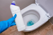 Tiszta WC tisztítószerrel, fehérítő géllel és kesztyűs kézzel. A koncepció az otthoni takarítás, takarítás