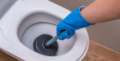 Egy tiszta WC tisztítószerrel és egy kesztyűs kéz dugattyúval. A koncepció az otthoni takarítás, takarítás
