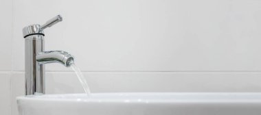 Banyodaki musluktan su akar. Krom tesisat ve seramik lavabo fayans arka planı