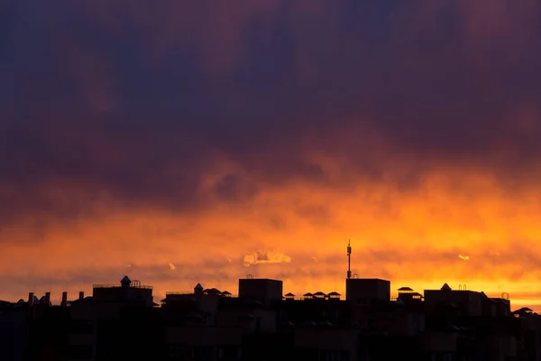 Roze oranje paarse zonsondergang boven de stad. Veelkleurige hemel en zwart silhouet hoge gebouwen van de metropool — Stockfoto