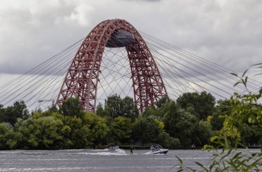Moskova'da bulutlu bir günde pitoresk köprü. Moskova nehri üzerinde yüzen tekneler