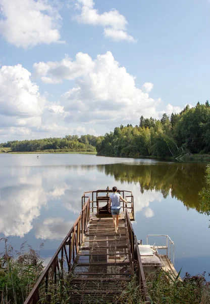 Clouds are reflected in the river. Beautiful river landscape. A small technological bridge, device for water discharge.  Beautiful river landscape. Reflection of clouds in water. The surface of the water