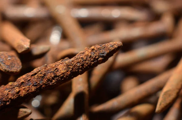 heaps of used nails made of rusty iron material are brown mixed with black spots and an uneven shap