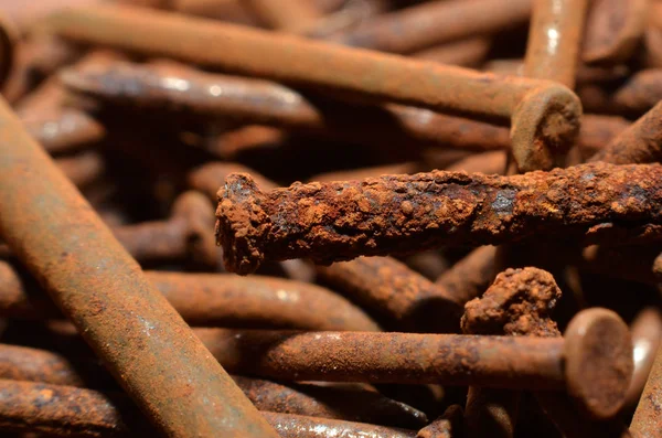 heaps of used nails made of rusty iron material are brown mixed with black spots and an uneven shap