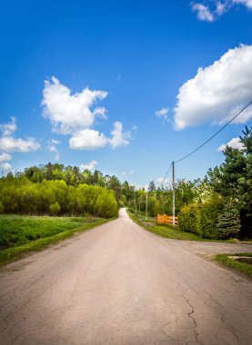 Kırsal manzara. Uzun düz yolda, orman ve mavi gökyüzü.