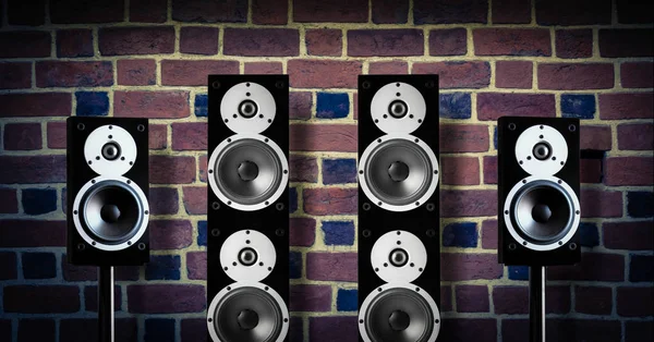 Black high gloss music speakers on brick wall