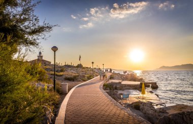 Makarska, Hırvatistan - 14 Temmuz 2018: İnsanlar güzel gün batımı Akdeniz Makarska, Hırvatistan için arka planda deniz feneri ile keyfini çıkarın