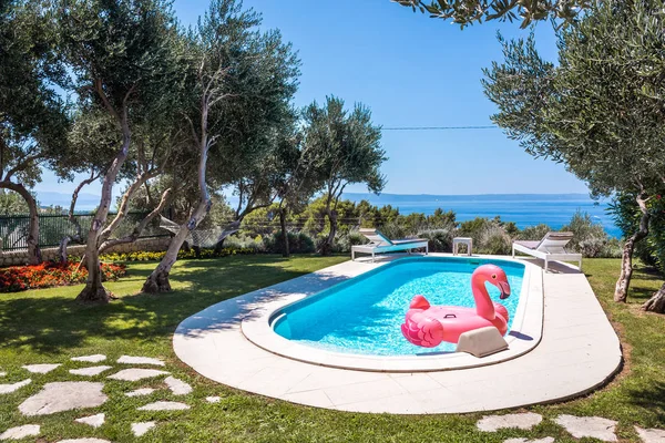 Pink flamingo waterbed in swimming pool with mediterranean sea in the background