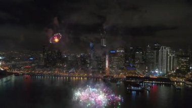 Parlak aydınlatma cityscape silüezeminkaranlık gece gökyüzünde patlayan çarpıcı renkli havai fişek