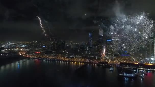 令人印象深刻的五颜六色的烟花爆炸在黑暗的夜空在明亮的照明城市景观天际线背景 — 图库视频影像