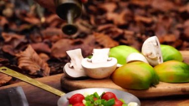 Adam el ormanda ahşap tahta üzerinde taze kesilmiş sebze salatası domates biber soğan ile kaseye yağ ve tuz dökerek