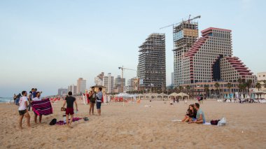 Tel-Aviv / İsrail - Kasım 2017: insanlar plajda akşam dinlenme. Yeni otel arka planda inşa ediliyor