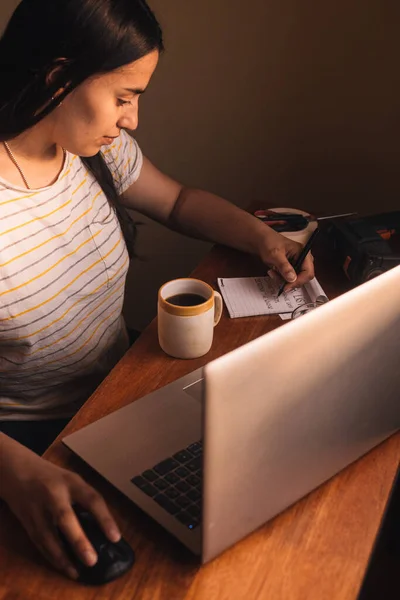 Woman planning home repairs with a cup of coffee, a chore list, a laptop and tools around