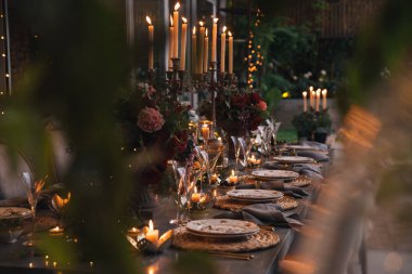 Mumlar, çiçekler ve cam bardaklarla dolu Noel masası..