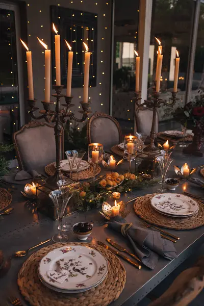 Mumlar, çiçekler ve cam bardaklarla dolu Noel masası..