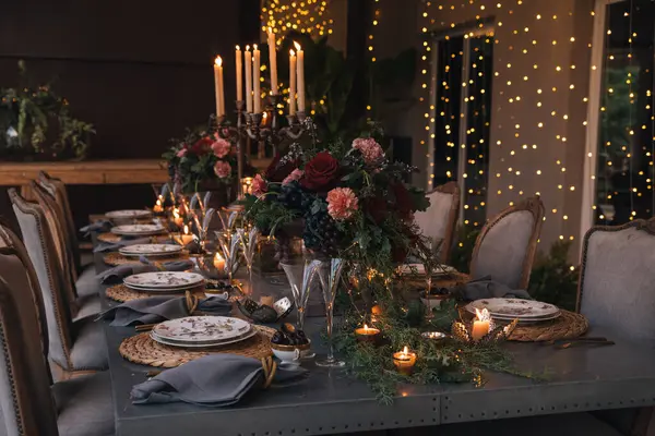 Mumlar, çiçekler ve cam bardaklarla dolu Noel masası..