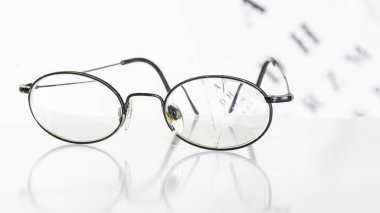 Beyaz bir odada bir masada eski gözlük.