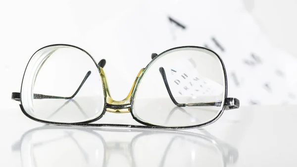 Óculos velhos em uma mesa em um quarto branco . — Fotografia de Stock