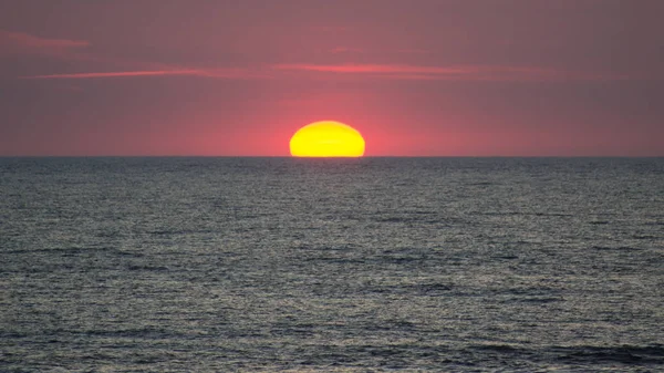 Le soleil couchant touche l'horizon rouge . — Photo