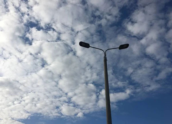 Street lamp post with two lanterns on the background of the picturesque sky with cirrus clouds