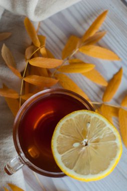 Tahta masada sonbahar yapraklı limonlu bir bardak çay.